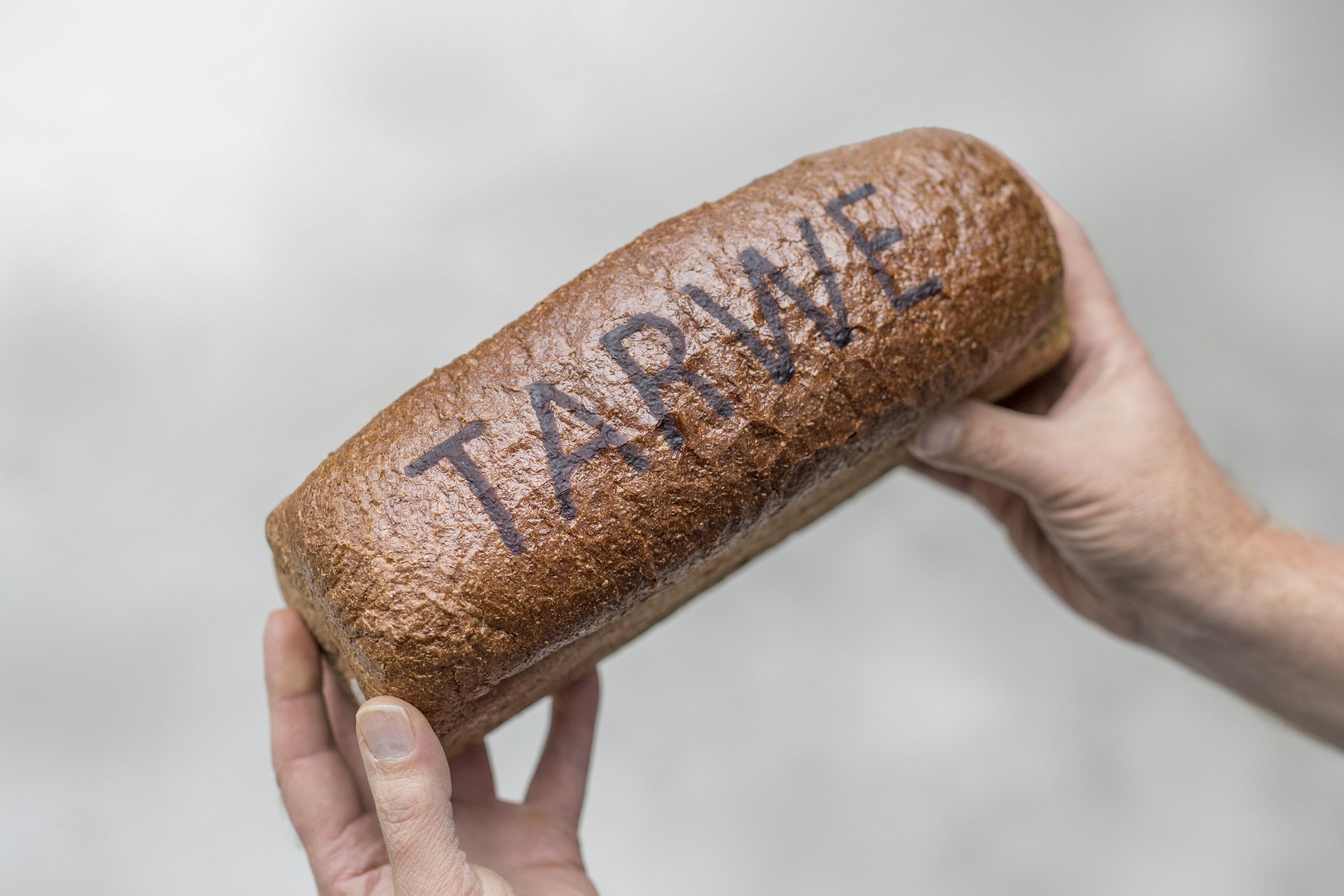 Wheat loaf with the word TARWE in baked RudinJet paste, held in two hands