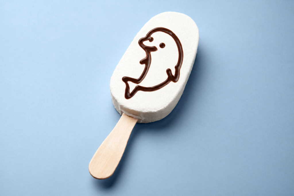 White ice cream bar on a stick decorated with a chocolate dolphin outline