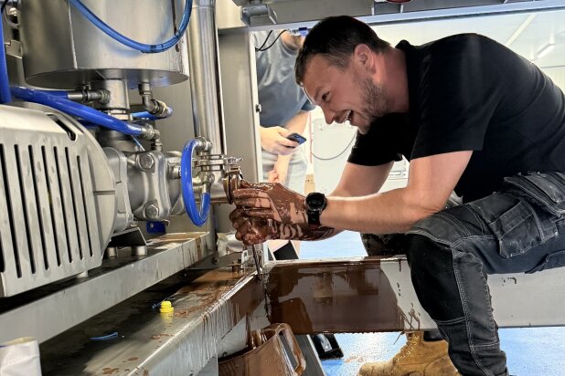 FoodJet engineer under a depositor, laughing, with his hands covered in chocolate