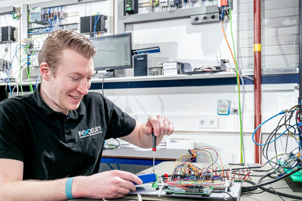 FoodJet engineer smiling while working on control electronics in the electronics workshop